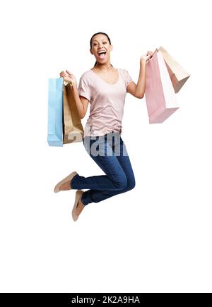 Jour de paie. Photo d'une jeune femme attrayante tenant des sacs de shopping et sautant dans l'air isolé sur blanc. Banque D'Images