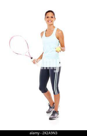 Prêt à jouer. Portrait d'une jeune femme heureuse prête pour son match tout en tenant une raquette et un ballon de tennis. Banque D'Images