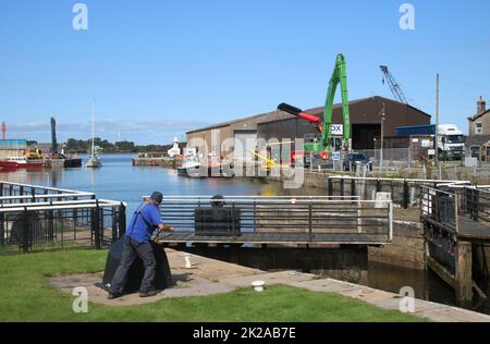 Opening lock gates to for a yacht entering through open entrance to Glasson Dock to pass from the dock through to the canal basin, September 2022. Stock Photo