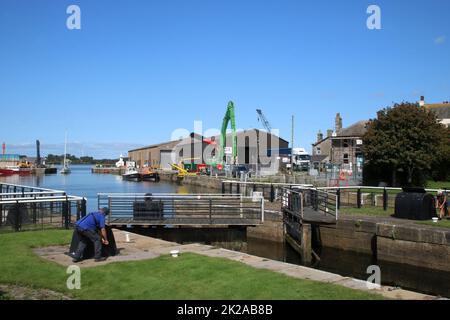 Opening lock gates to for a yacht entering through open entrance to Glasson Dock to pass from the dock through to the canal basin, September 2022. Stock Photo