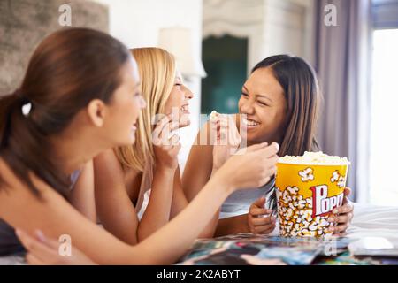 Nous avons fait cela dans les âges. Photo de trois jeunes femmes séduisantes mangeant du pop-corn la nuit des filles. Banque D'Images