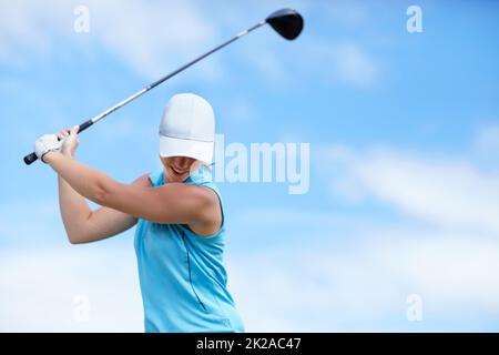 L'astuce est de garder la tête basse. Une jeune golfeuse balançant un club de golf (pilote) sur sa tête sur le point de prendre un coup - espace d'imitation. Banque D'Images