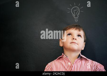 HES a eu beaucoup d'idées. Photo en studio d'un jeune garçon avec une ampoule à dessin de craie au-dessus de sa tête. Banque D'Images