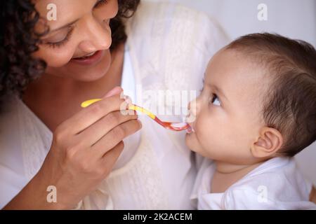 Elle connaît sa saveur préférée. Une petite fille mignonne qui est nourrie par sa mère. Banque D'Images