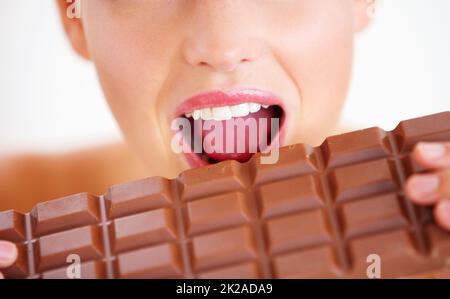 On y va pour un petit morceau Vue rognée d'une jeune femme piquant dans une grande plaque de chocolat. Banque D'Images