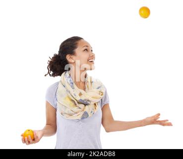 Ses a eu l'œil sur l'équilibre d'une alimentation saine. Jeune femme souriant tout en jonglant avec des oranges fraîches. Banque D'Images