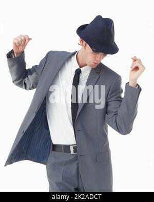 En un clin d'œil et en mode aléatoire. Un jeune homme en costume et chapeau dansant sur fond blanc. Banque D'Images