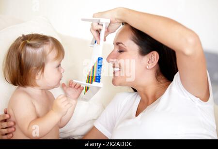 Combien. Une jeune mère tenant un abacus jusqu'à sa petite fille. Banque D'Images