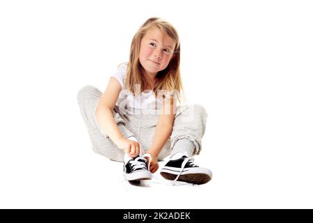 Saviez-vous que je peux attacher mes propres lacets ? Photo d'une petite fille mignonne isolée sur blanc. Banque D'Images