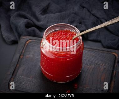 caviar rouge granuleux frais dans un pot en verre sur une table en bois Banque D'Images