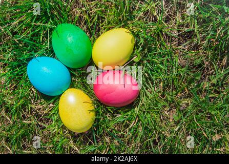 Vue de dessus d'un bouquet d'œufs de Pâques colorés posés sur l'herbe de printemps verte. Style plat, concept de vacances de Pâques Banque D'Images