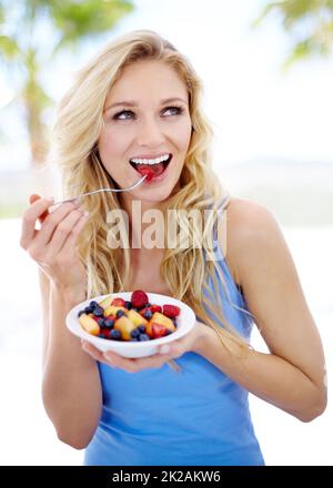 Un régime qu'elle peut apprécier. Jolie jeune femme appréciant sa salade de fruits. Banque D'Images