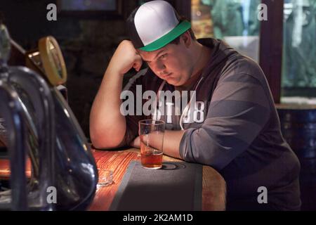 La vie vous fait tomber. Un jeune homme qui regarde seul le bar. Banque D'Images