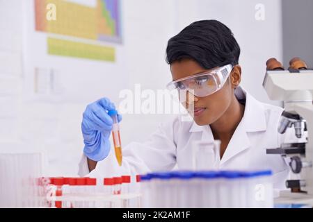 Travail quotidien. Un beau jeune scientifique qui dépose une substance dans des tubes à essai dans son laboratoire. Banque D'Images