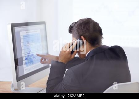 Regardez le cours de ces actions. Photo d'un homme d'affaires parlant au téléphone et pointant vers un graphique sur son écran d'ordinateur. Banque D'Images