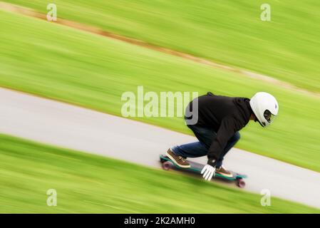 Il vit la vie dans la voie rapide. Photo d'un homme qui fait du skateboard sur une voie à grande vitesse sur son plateau. Banque D'Images