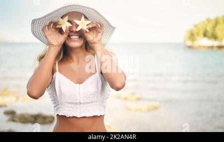 Nous nous sentons comme une star aujourd'hui. Photo courte d'une jeune femme attrayante debout et jouée, tenant des morceaux d'ananas en forme d'étoile contre les yeux. Banque D'Images