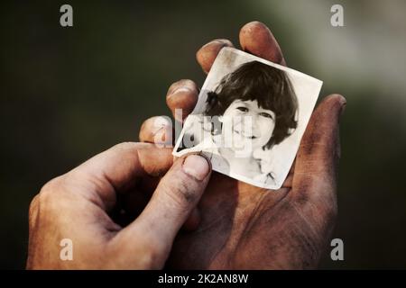 Mon fils me manque tellement. Une main sale tenant une image noire et blanche d'un petit garçon. Banque D'Images