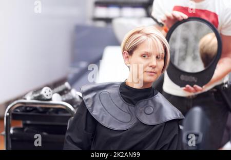 Je suis heureux de cela, Merci. Une femme qui examine sa coupe de cheveux dans le miroir du coiffeur. Banque D'Images