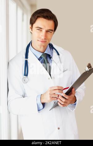 Médecin attentif avec stéthoscope et bloc-notes en regardant loin. Portrait d'un jeune médecin attentif avec stéthoscope et bloc-notes en regardant loin. Banque D'Images