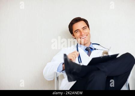 Médecin détendu avec un stéthoscope et un bloc-notes. Un jeune médecin détendu avec un stéthoscope et un bloc-notes à l'hôpital. Banque D'Images