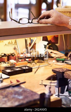 Besoin d'une vision parfaite pour le travail de précision à venir. Vue rognée d'un artisan qui se trouve devant ses lunettes sur son poste de travail. Banque D'Images