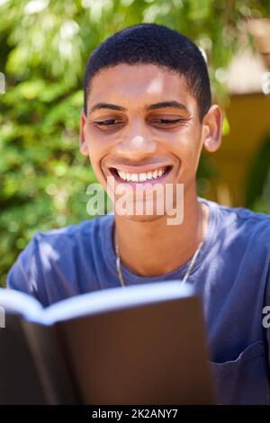 Donner le ton de la journée avec l'Evangile. Plan court d'un beau jeune homme assis seul à l'extérieur et lisant un livre pendant la journée. Banque D'Images