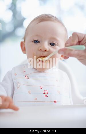 Désordonné et adorable. Image rognée d'un bébé garçon nourri par sa mère. Banque D'Images