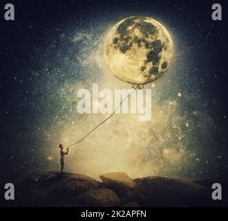 Scène surréaliste et inspirante avec une personne tenant la pleine lune comme un ballon avec une corde. Vue imaginaire rêveuse sur le ciel étoilé de nuit Banque D'Images