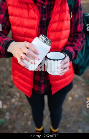 Une fille verse le thé chaud d'un thermos, une collation en plein air.Voyage, trekking et randonnée. Banque D'Images