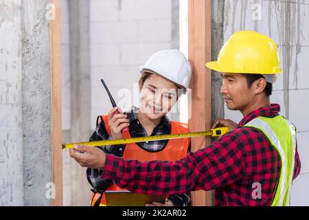 Hommes ouvriers de construction industrielle processus d'installation mesure porte en bois avec mètre ruban Banque D'Images