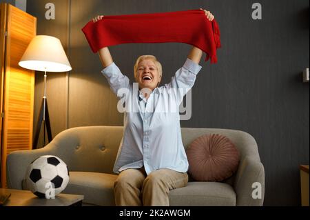 Un ballon de football aux personnes âgées surjoyeusement tenant un foulard sur la tête Banque D'Images