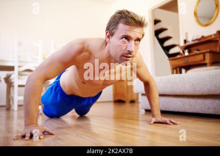 Déterminé à atteindre 100. Un jeune homme charmant qui fait des push-ups à la maison. Banque D'Images