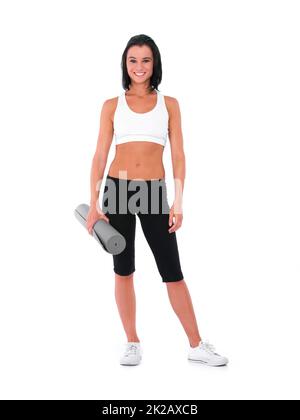 Shes en forme. Une jeune femme en bonne santé souriant tout en tenant un tapis de yoga - isolé sur blanc. Banque D'Images