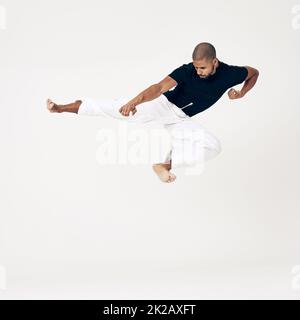 L'habitude de la persistance est l'habitude de la victoire. Photo en studio d'un jeune artiste martial pratiquant. Banque D'Images