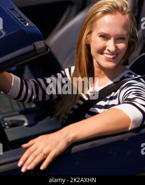 Mettons la pédale sur le métal. Photo d'une jeune femme volant dans une voiture de sport. Banque D'Images