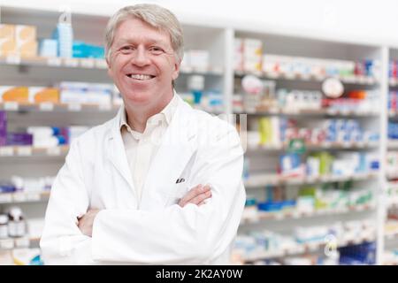 Pharmacien souriant en toute confiance. Portrait d'un pharmacien confiant souriant avec les mains pliées en pharmacie. Banque D'Images