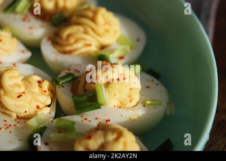 Oeufs découpés saupoudés de paprika et d'oignon vert haché sur une assiette verte sur une table de courge .Vue de dessus Banque D'Images