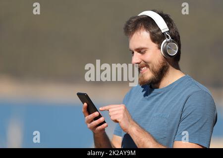 Homme écoutant de la musique dans la nature vérifiant le téléphone Banque D'Images