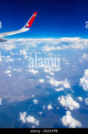 Vol avec Nepal Airline au-dessus des nuages au-dessus de la campagne de la Thaïlande. Banque D'Images