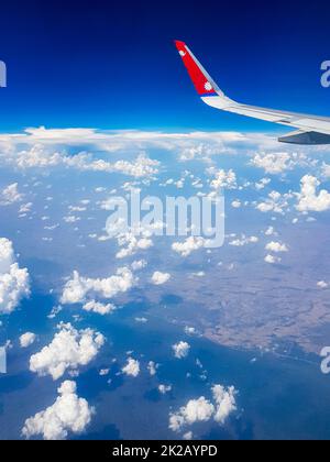 Vol avec Nepal Airline au-dessus des nuages au-dessus de la campagne de la Thaïlande. Banque D'Images