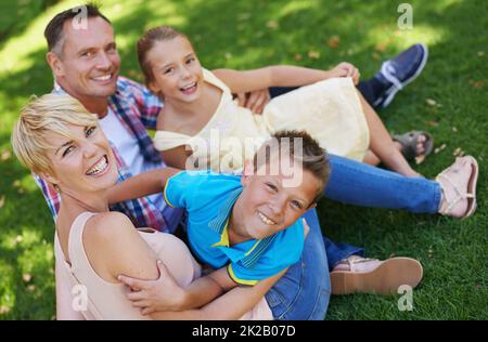 C'est un été mémorable. Un portrait d'une famille heureuse assise sur l'herbe ensemble lors d'une journée ensoleillée. Banque D'Images