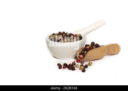 Mortier et pilon avec grains de poivre mélangés sur fond blanc Banque D'Images