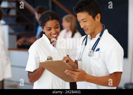 Notre objectif est d'aider les autres à s'améliorer. Cliché de deux médecins qui dictent le diagnostic du patient. Banque D'Images