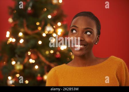 Des idées festives. Photo d'une jeune femme attrayante debout devant un arbre de Noël. Banque D'Images