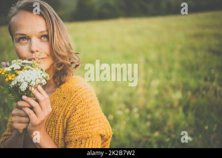 Belle jeune femme à l'extérieur avec un bouquet de fleurs sauvages dans un champ, profiter de la nature. Happy Woman on spring meadow Banque D'Images