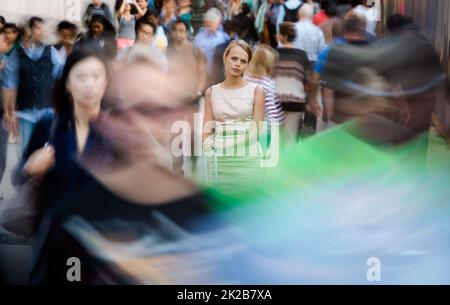 Foule de personnes marchant dans la rue de la ville - mouvement image floue avec des visages méconnaissables - jeune femme debout, debout, se sentant, déprimé Banque D'Images