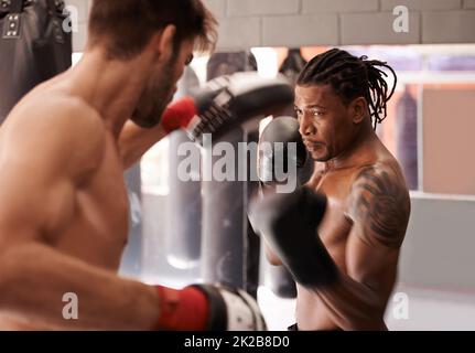 Des partenaires de boxe dédiés. Photo d'un jeune boxeur pratiquant sa perforation avec un partenaire. Banque D'Images