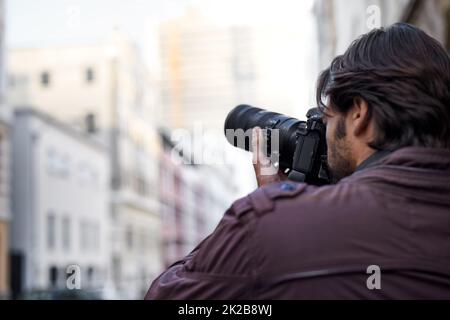 Capturer la beauté qui l'entoure. Un jeune homme prenant une photo avec son appareil photo. Banque D'Images