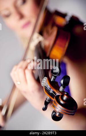 Enjouée par la beauté de la musique. Studio tourné d'une belle jeune femme jouant du violon. Banque D'Images